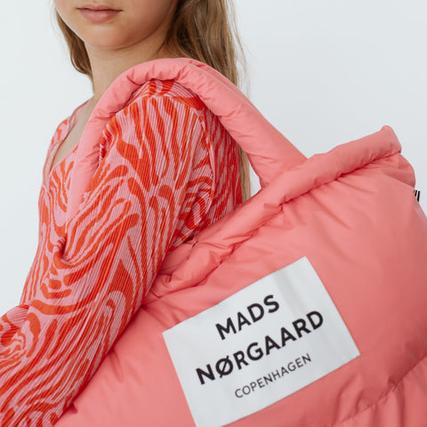 Model trägt Mads Nørgaard Recycle Pillow Bag in der Farbe Shell Pink aus der Spring Kollektion 2024
