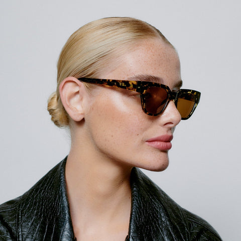 Frauen Model trägt A.Kjærbede Sonnenbrille Kaws KL2310 in der Farbe Black/Yellow Tortoise