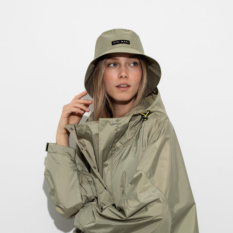 Model trägt Vivi Mari Raincoat und Bucket Hat in der Farbe pale olive. 